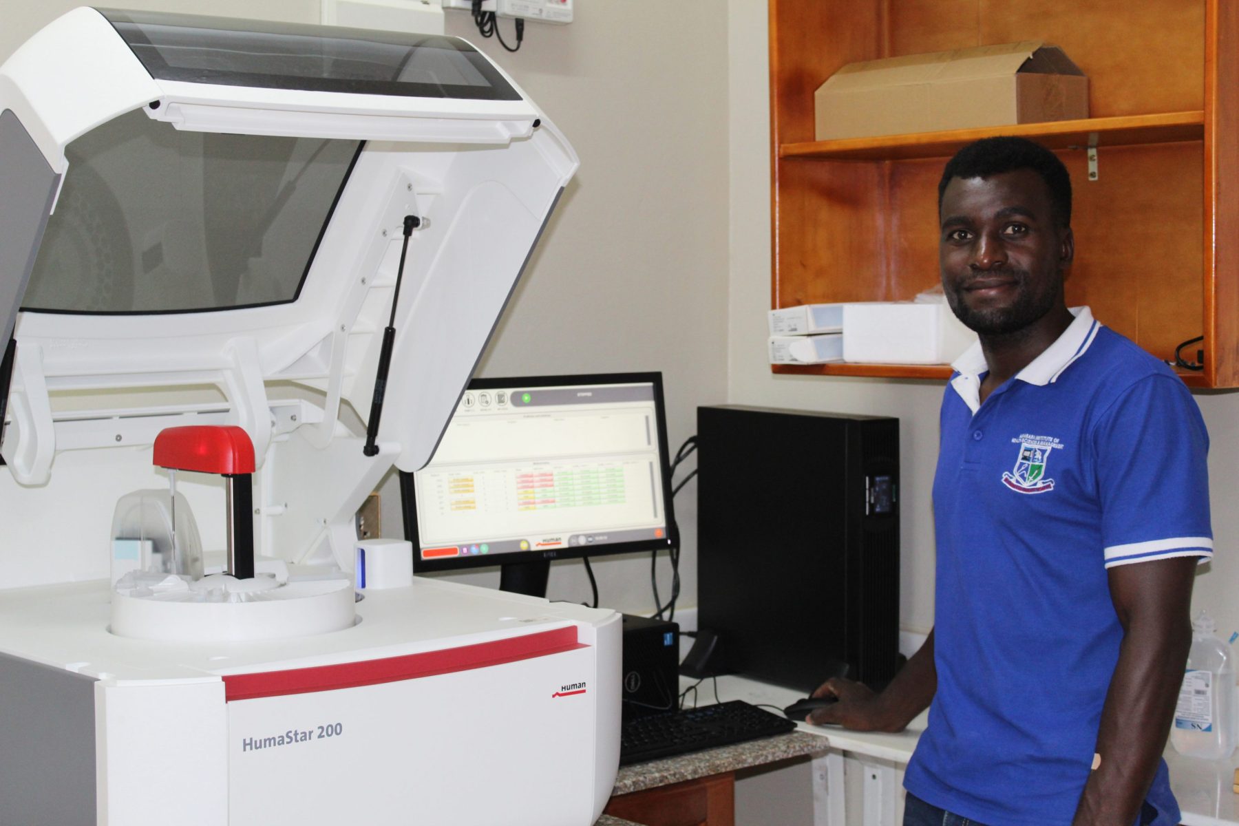 EWCV's lab technician is standing beside one of the brand new lab machines at EWCV Clinic.