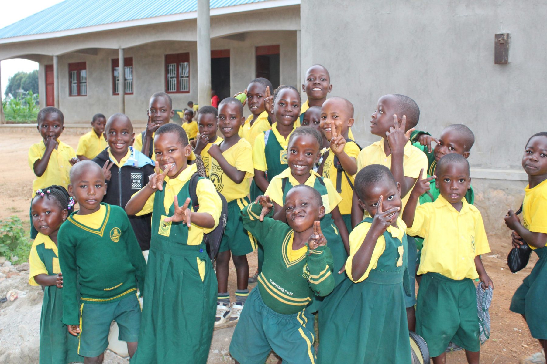 This photo shows a large group of happy, playful nursery students in their lovely green and yellow school uniforms!